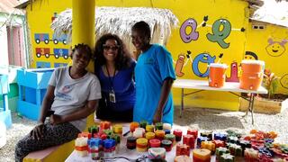 Alicia Morris '99 poses for a photo with two others in front of a colorful table of candles during a Yale Alumni Service Corps trip.